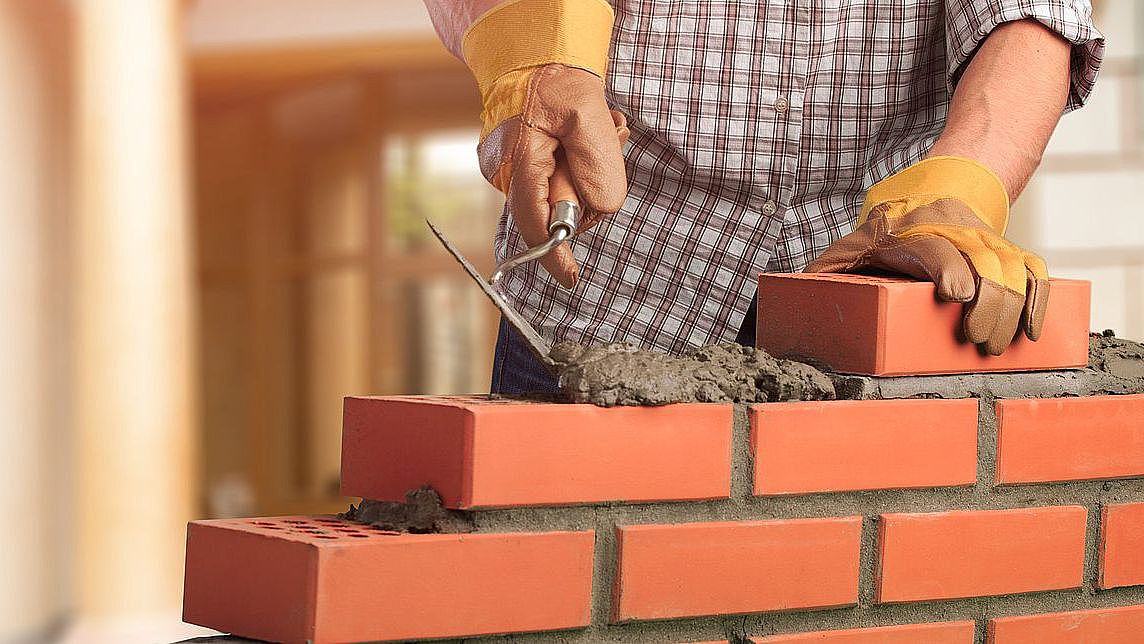 ein Arbeiter mauert eine Wand mit Ziegelsteinen