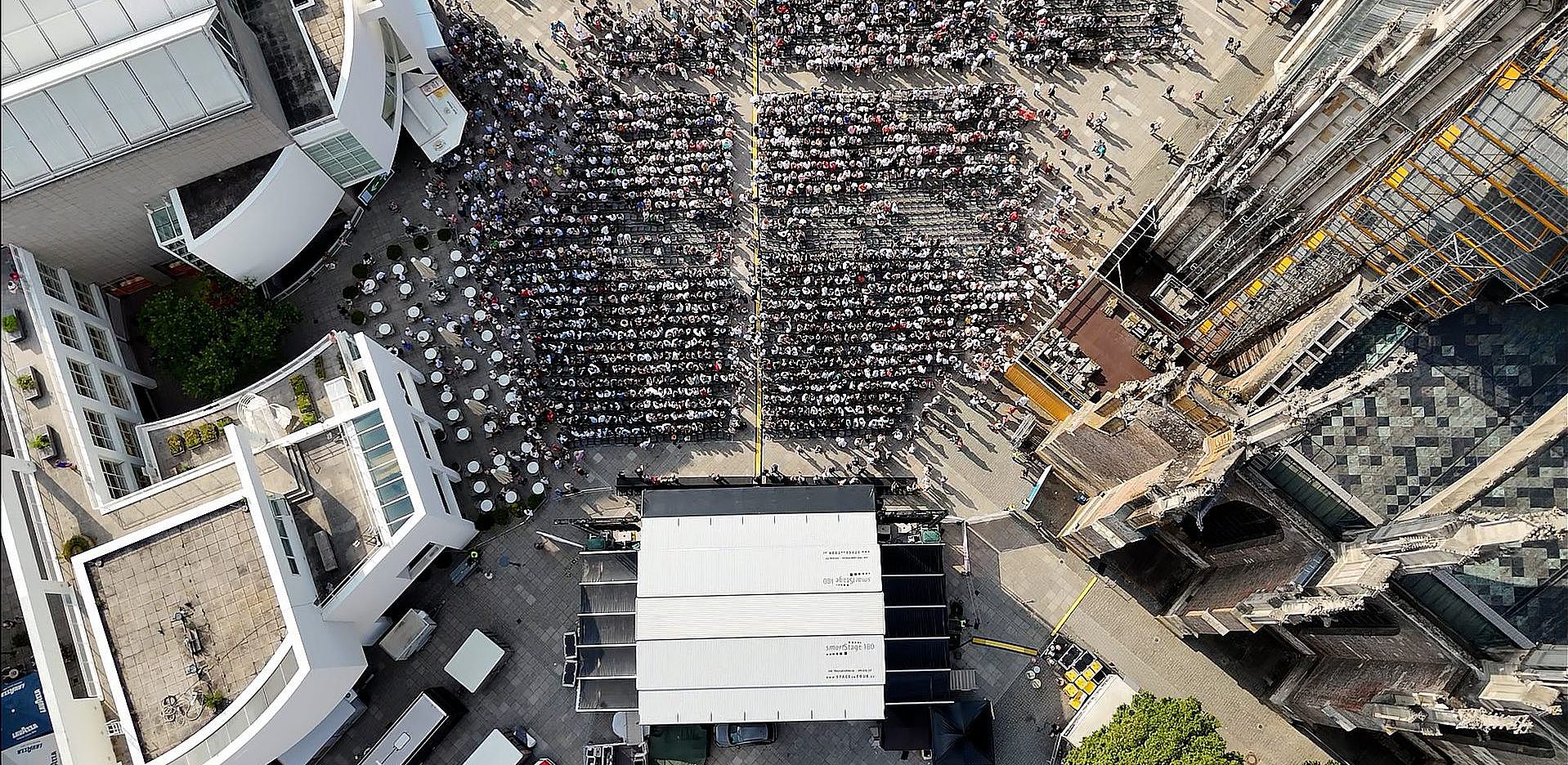 Drohnenaufnahme von Absolventinnen und Absolventen, die auf dem Münsterplatz sitzen