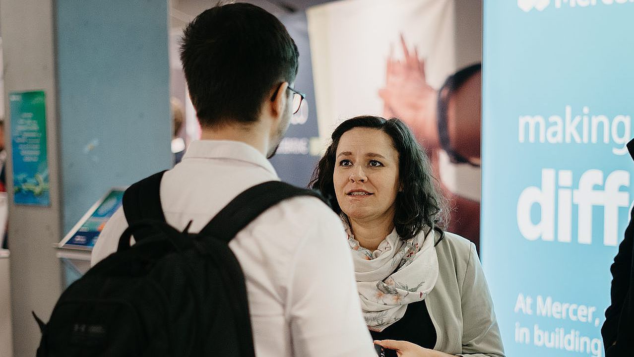 Ein Studierender spricht mit einer Firmenvertreterin auf dem WiMa Kongress 2024, in der Uni Ulm