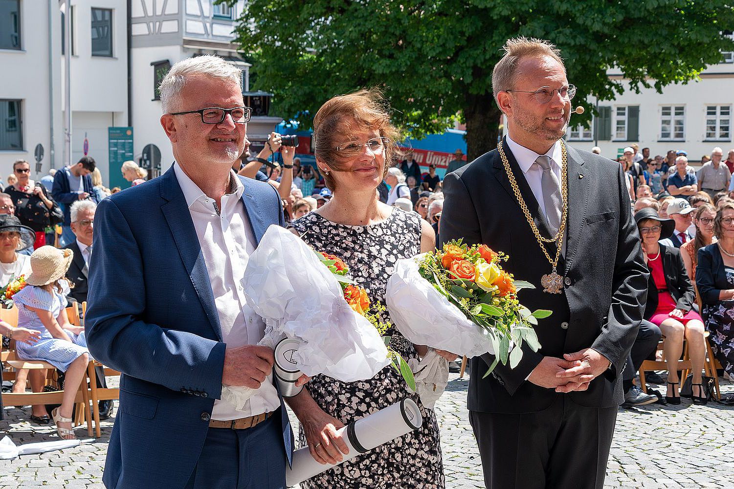 Foto von Prof. Maximilian Fichtner und Prof. Marianne von Schwerin, jeweils mit einem Blumenstrauß und ihrer Urkunde in den Händen; rechts neben ihnen steht Martin Ansbacher