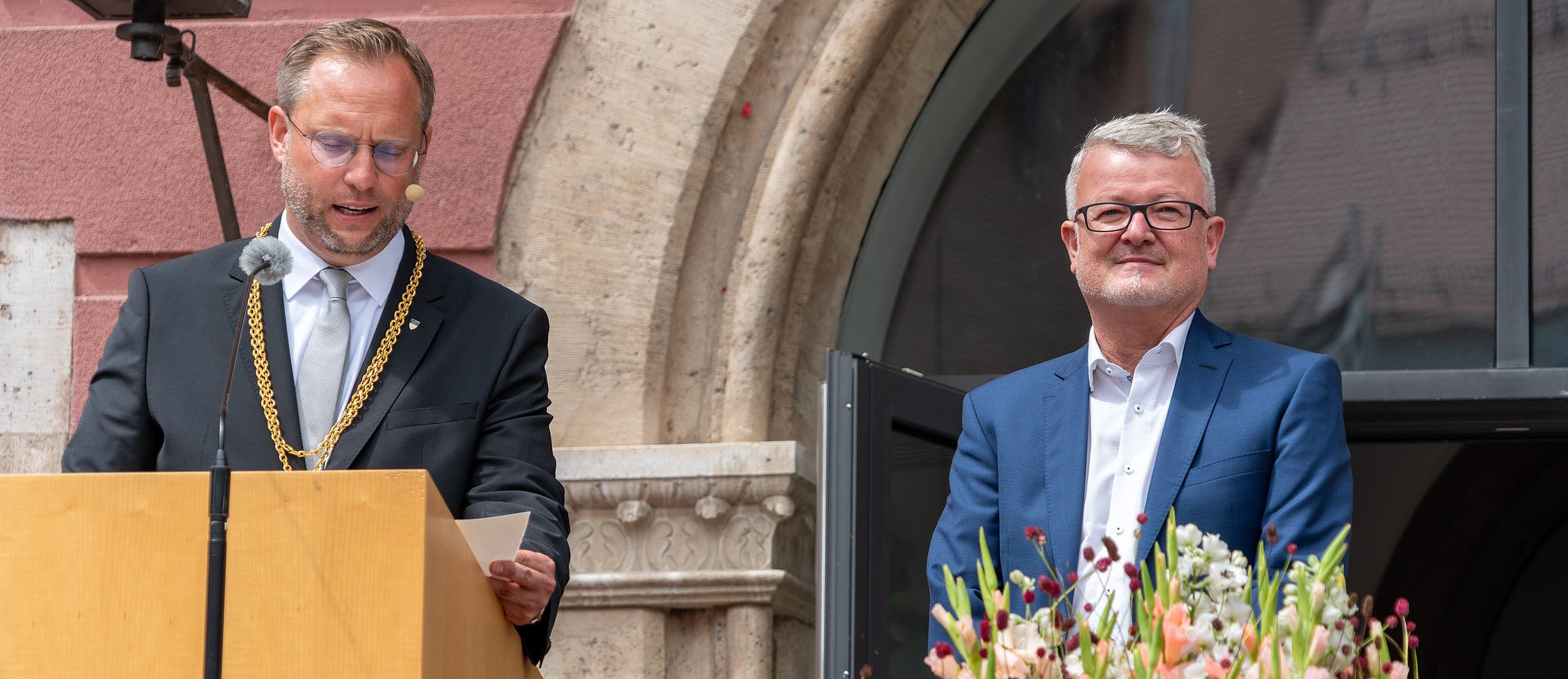 Foto von Oberbürgermeister Martin Ansbacher, der gerade den Urkundentext des Wissenschaftspreises 2024 verliest; rechts neben ihm steht Prof. Maximilian Fichtner 